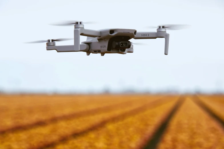 a large white remote controlled camera flying in the sky over a field