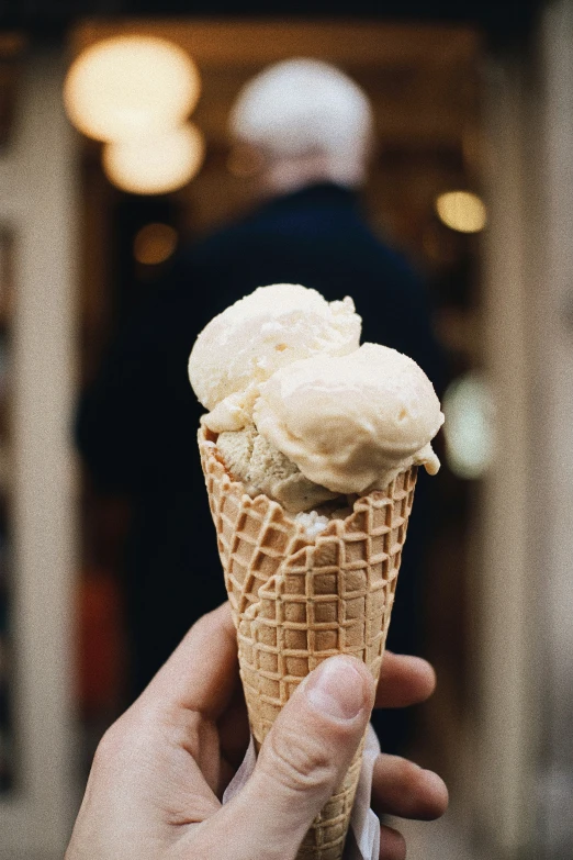 a person holding a chocolate waffle cone with white icing