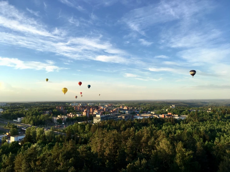 several  air balloons flying in the sky over a small town