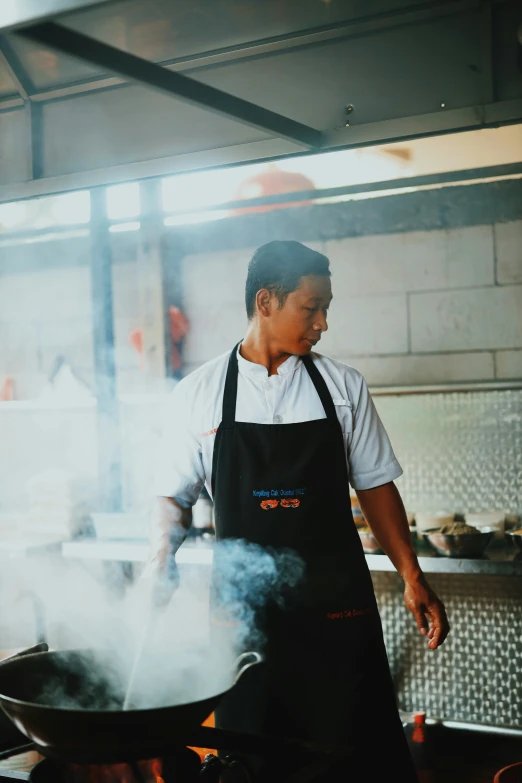 a man is cooking in a frying pan on a grill