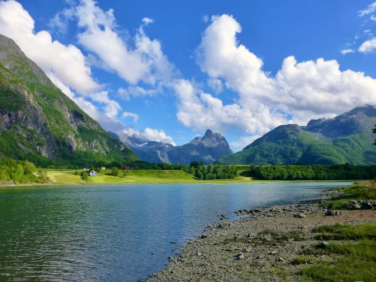 the clouds are flying over the mountains above the river