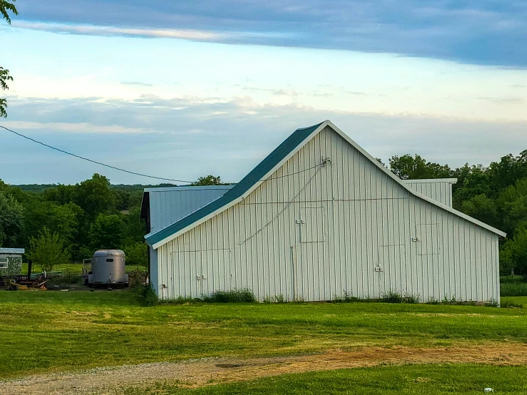 two farm sheds and one trailer sitting in the grass