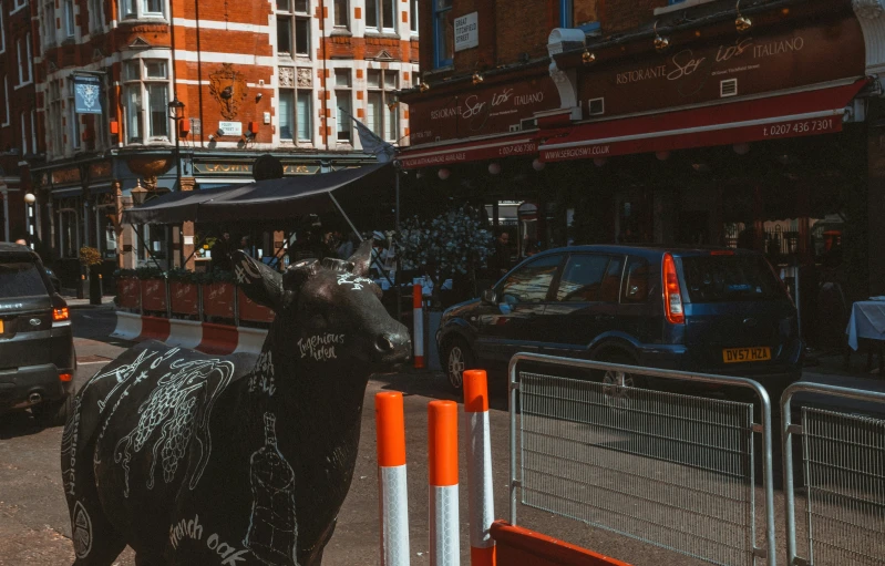 a statue of an animal holding a umbrella in the middle of a street