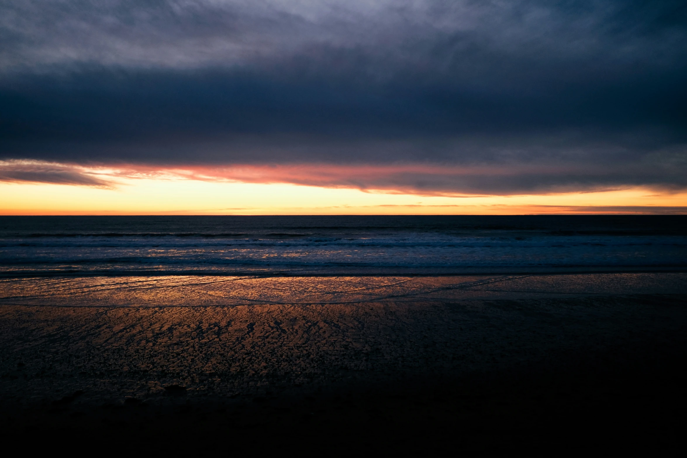 a beach with waves crashing on it at sunset