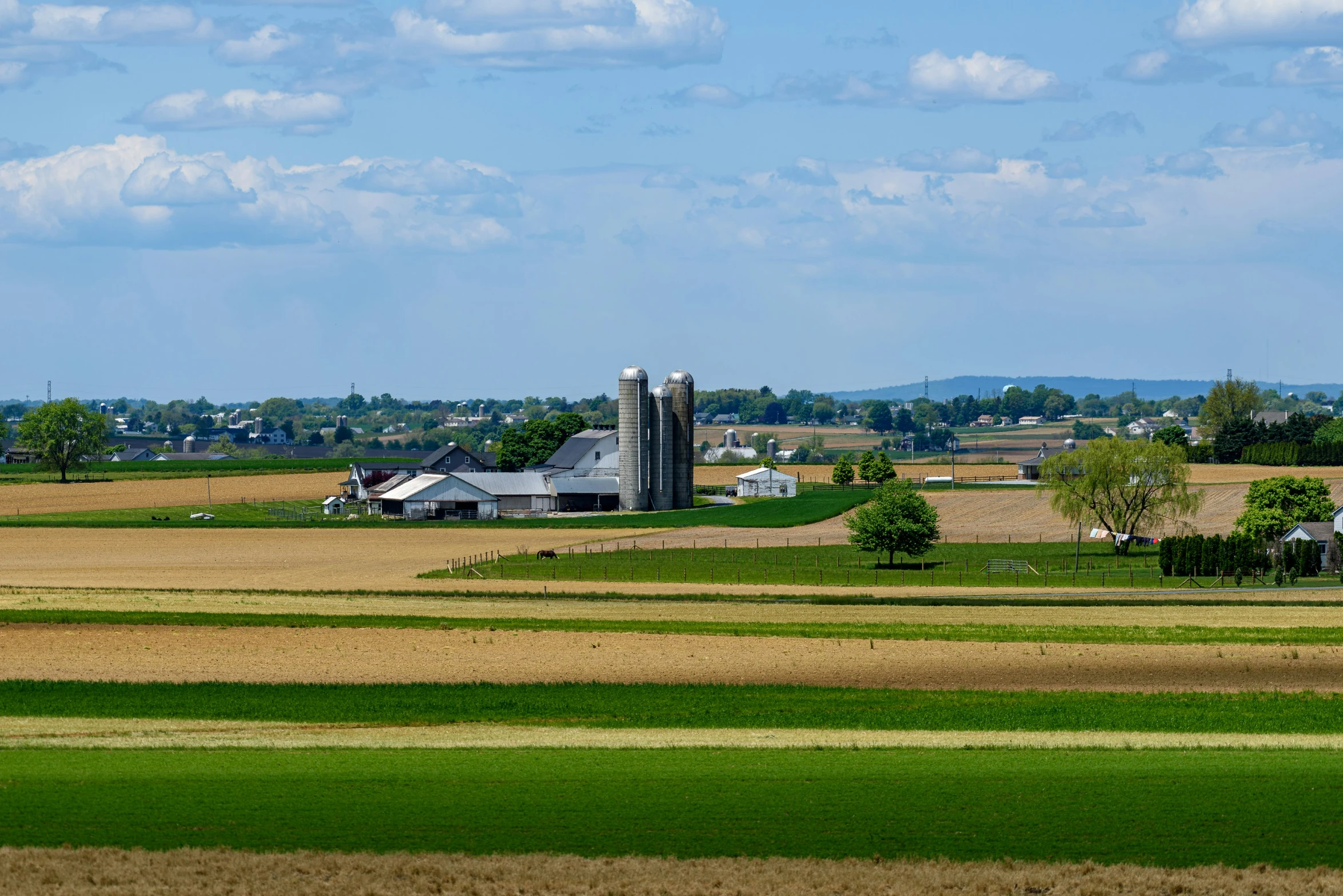 a barn sitting in a green field under a blue sky