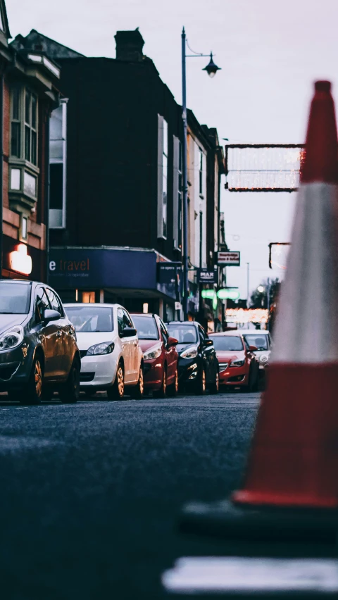 several cars parked on a street in front of traffic cone