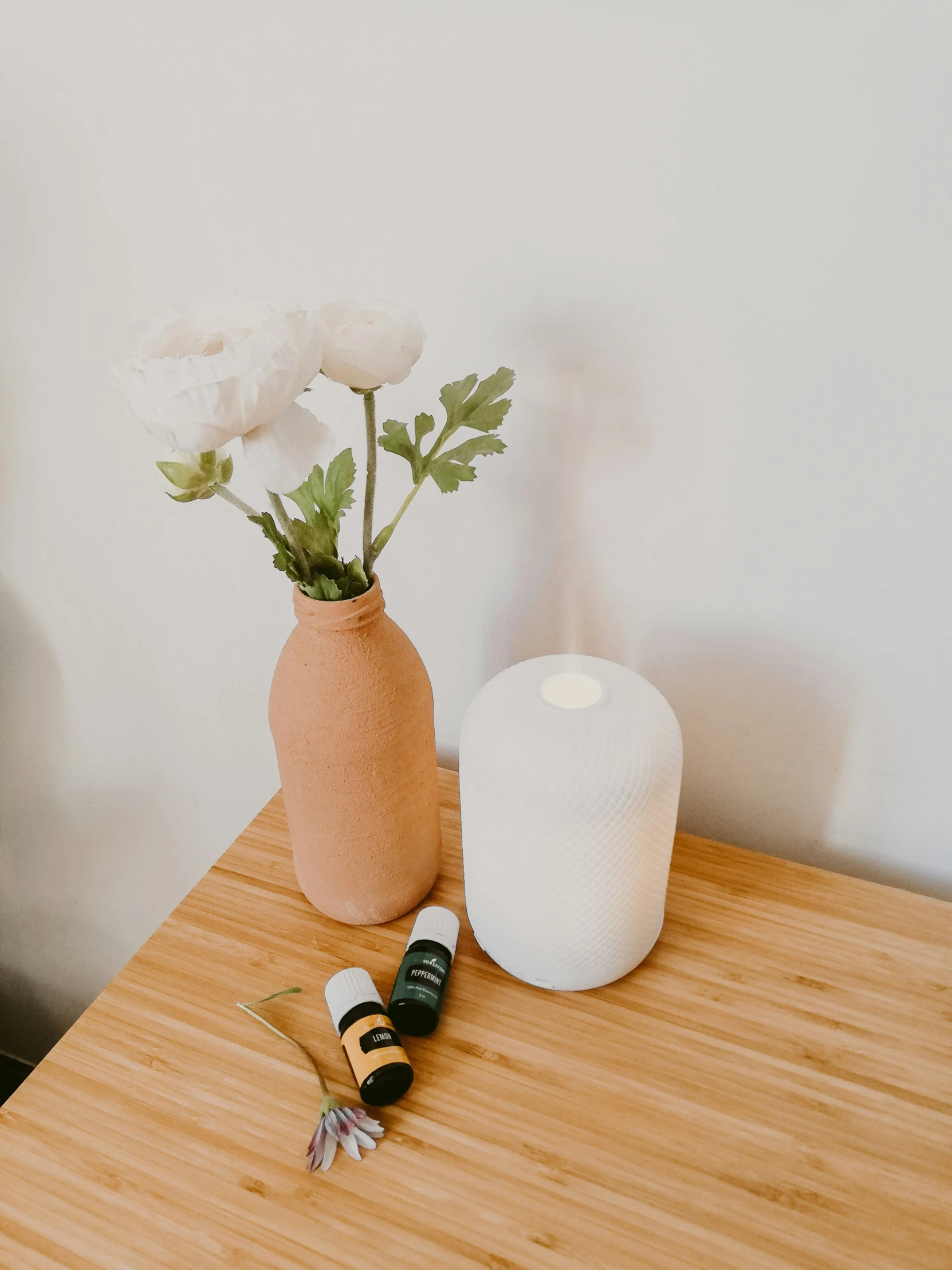 a white vase holding flowers on a wooden table