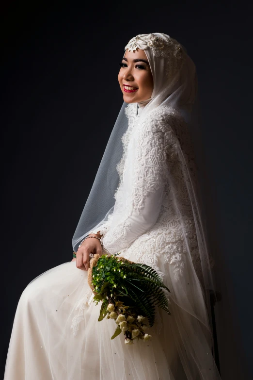 a bride sitting on a chair holding a bouquet of flowers