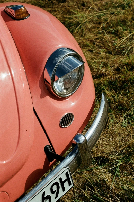 the front view of an old pink car in the grass