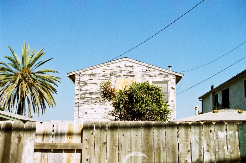 the side of a wooden fence with a small white building behind it