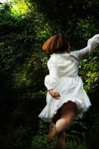 a woman in white dress flying through forest