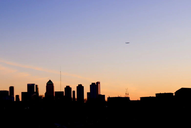 a view of a skyline at sunset with an airplane flying in the sky