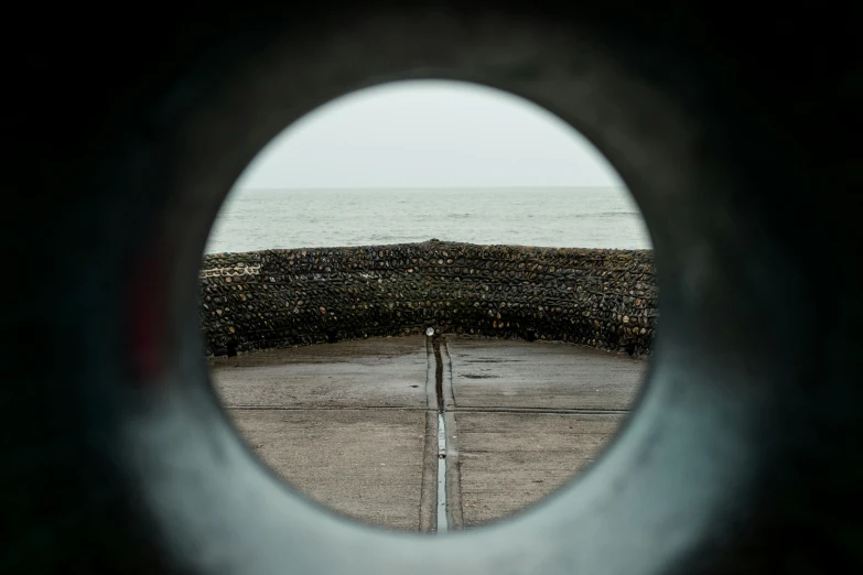 the view of the water out of a circular hole in a concrete structure