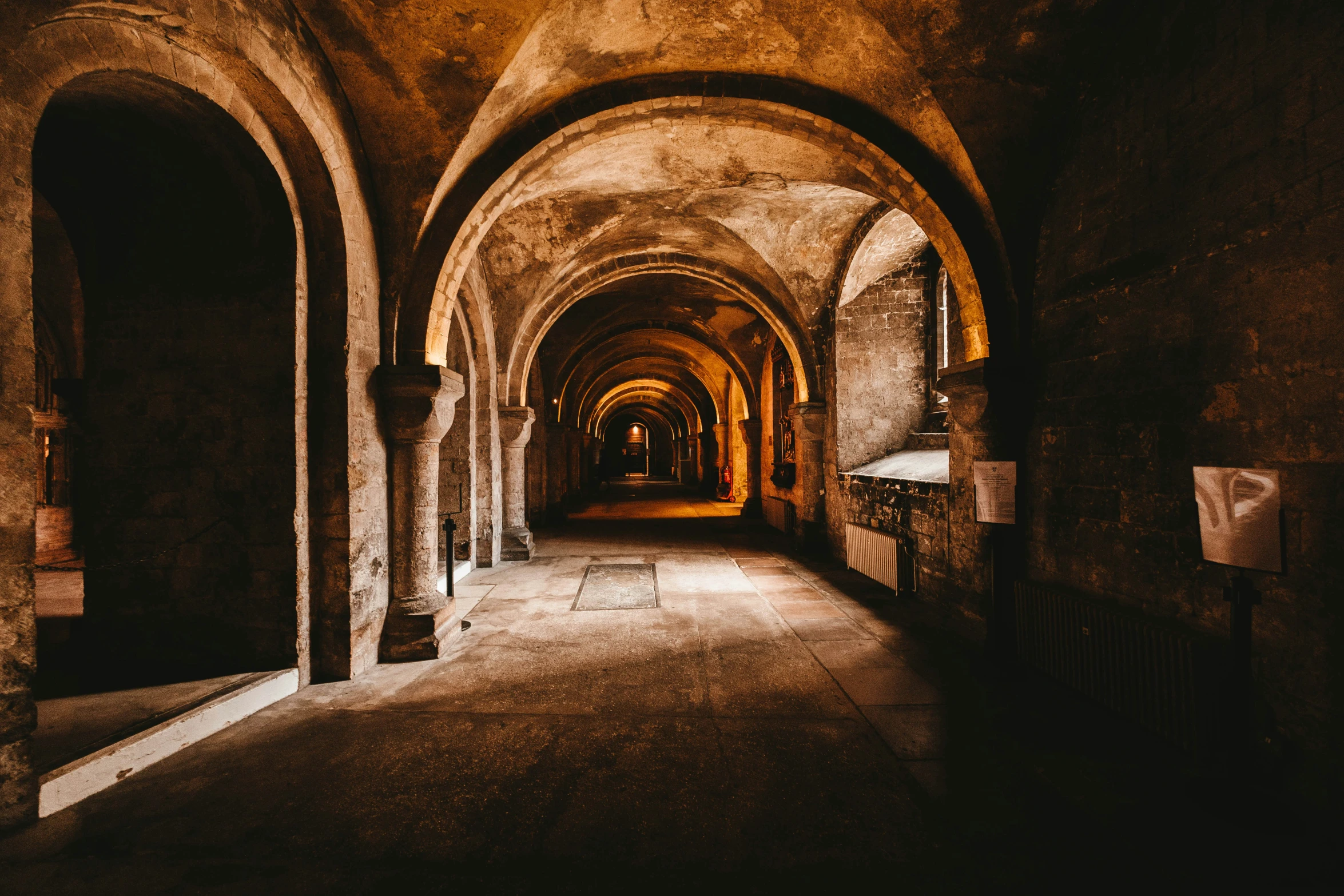 a long dimly lit passageway leading to a bench