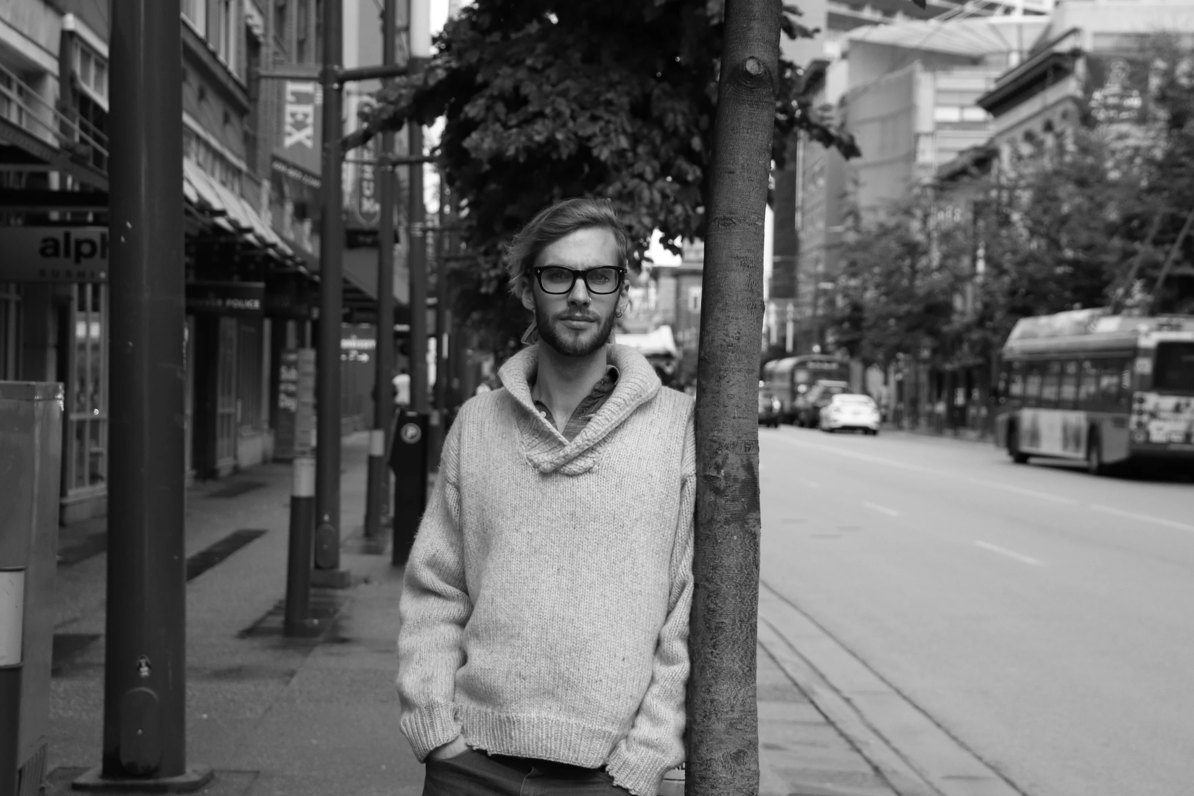 a man leaning up against a tree on the side of a street