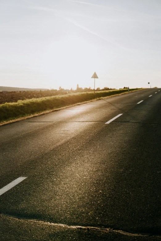 an empty road with the sun rising behind it