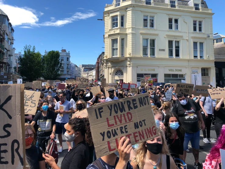 protesters with protest signs standing outside of a white building