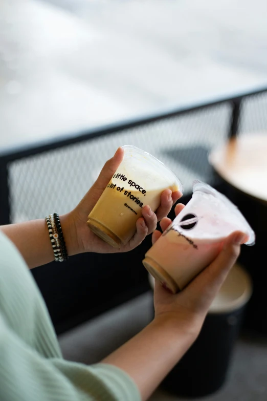 a woman is sitting and holding some paper cup