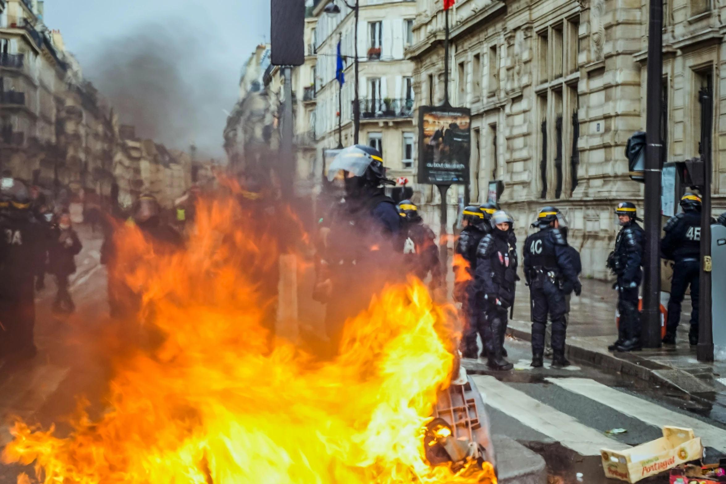 police officers stand around a blazing fire and smoke during the protest