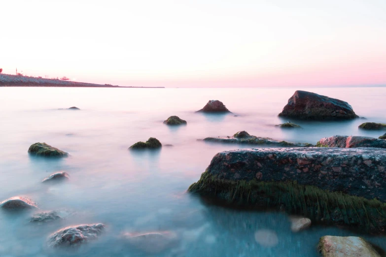 large rocks with a lighthouse on the shore near the water