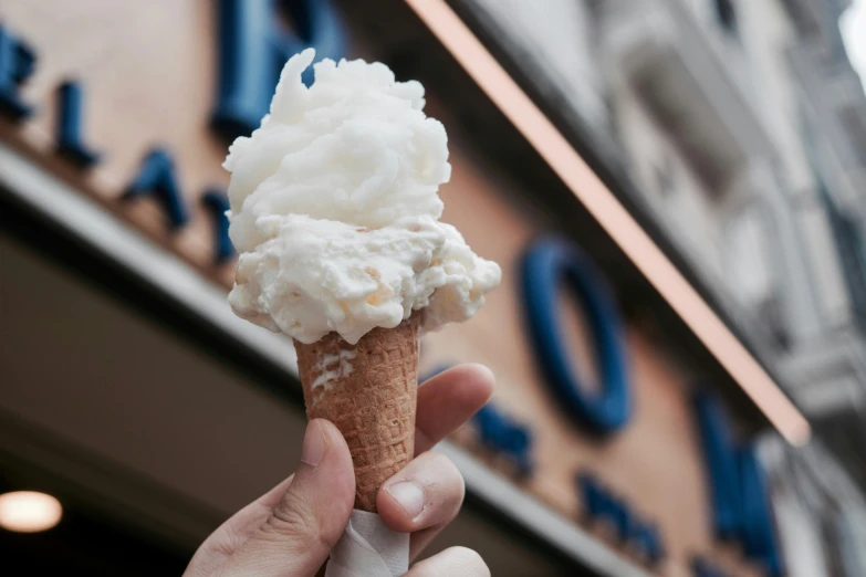 a hand holding a cone filled with whipped cream