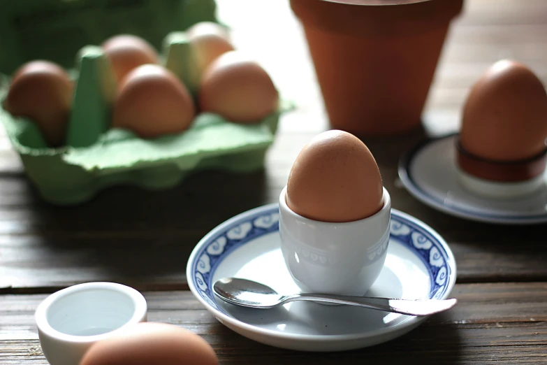 eggs in an egg cup and saucer on a table