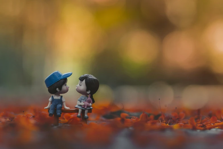 a boy and girl figurines sit on top of leaves