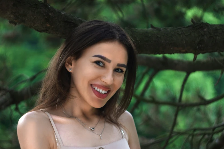 a woman smiles while leaning on the nches of a tree