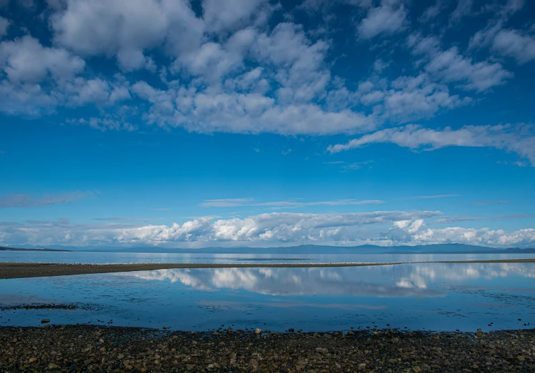 a body of water with clouds above it