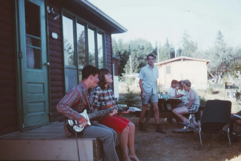 several people are gathered around talking and playing instruments