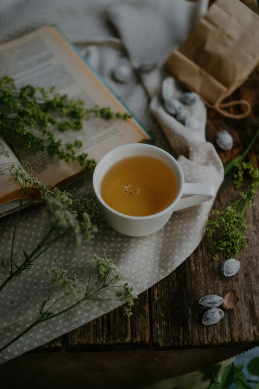 a cup of tea sits next to an open book