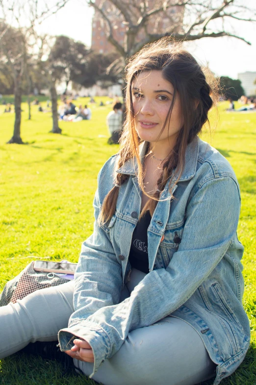 a woman sitting on a grass covered field