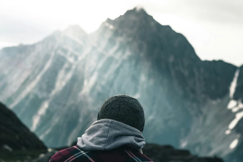 a person standing next to a mountain with a sky background