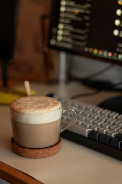 an coffee cup sits on a desk in front of a computer