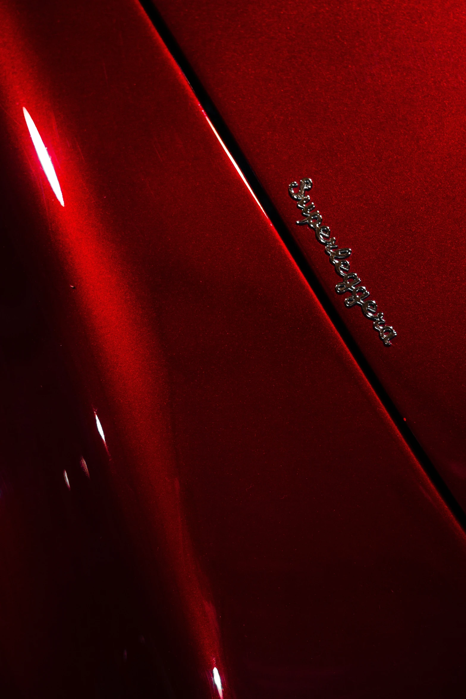 the hood and tail end of a red car with a badge