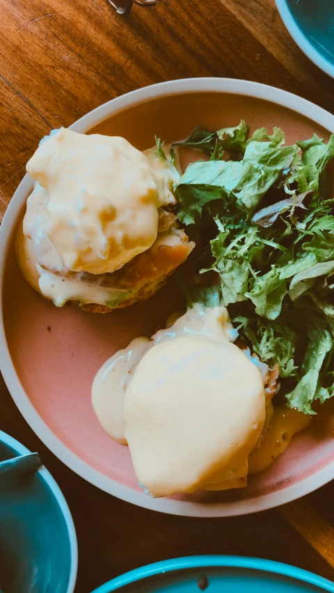 an egg sandwich sitting on top of a plate of salad