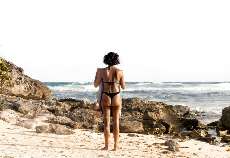 a women in bikini on sandy beach near rocks
