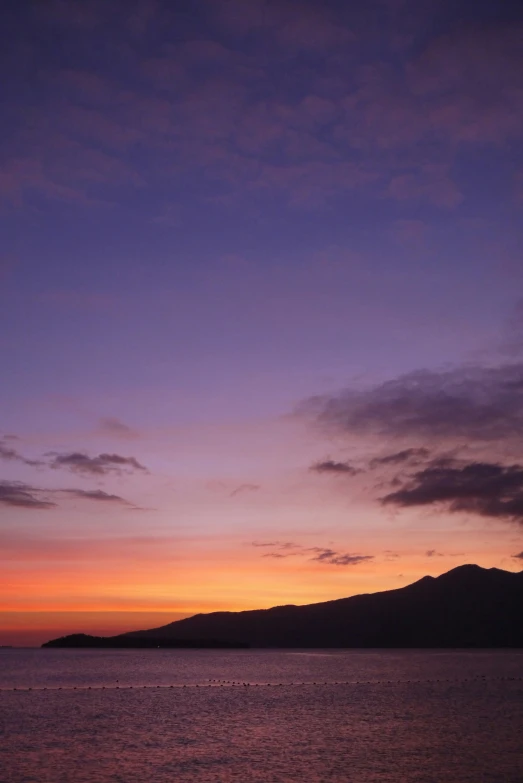 a sunset on the ocean with a lighthouse out in front