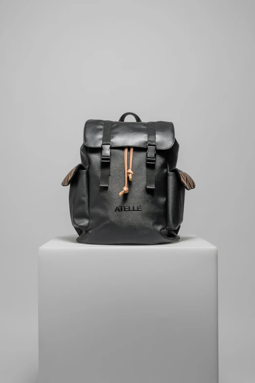 a black backpack on white pedestal and grey background