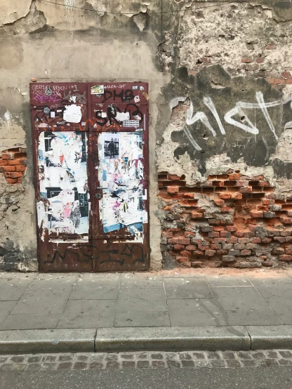 graffiti covered doors on the side of an old brick building