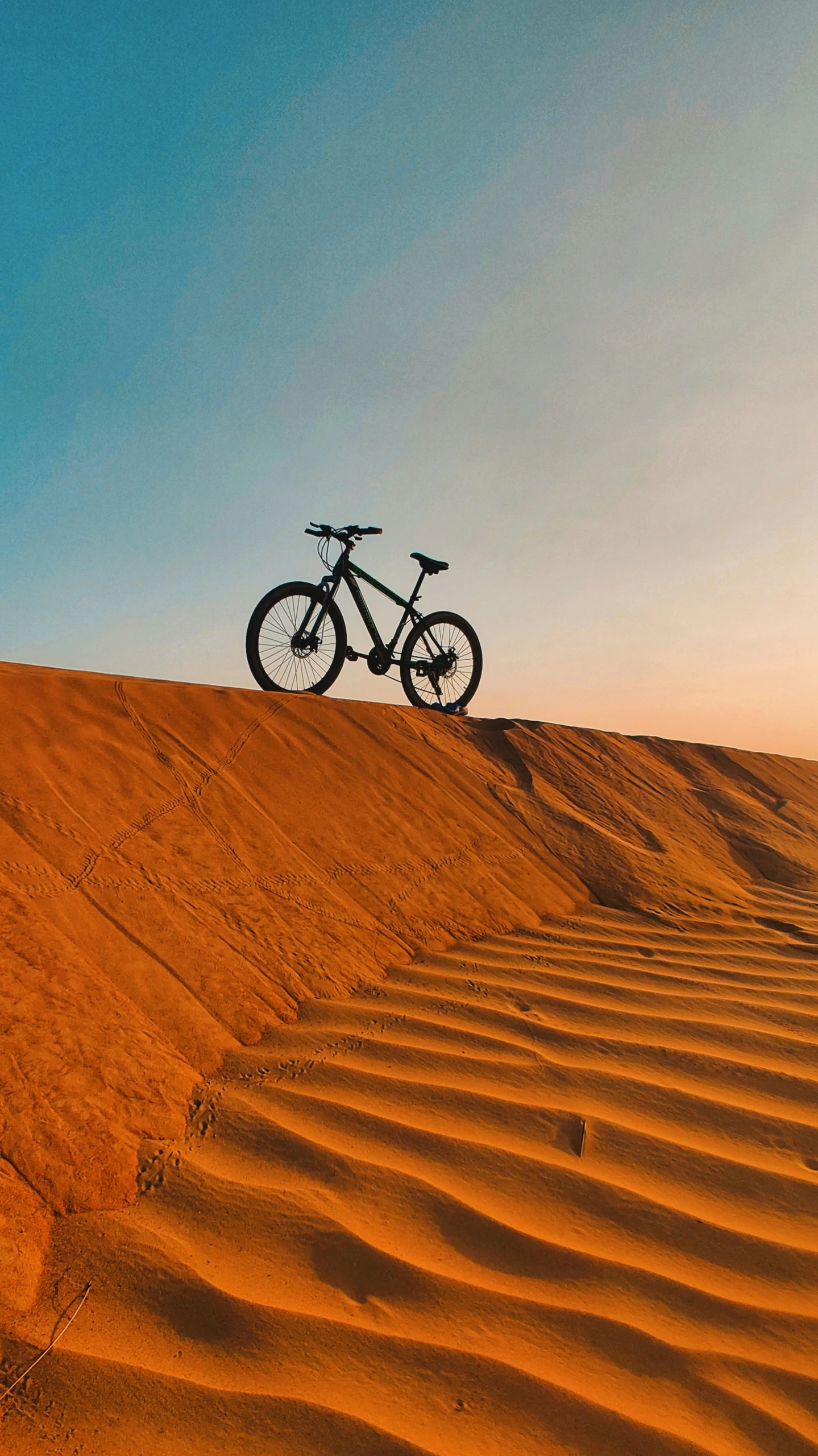 a bike sitting on top of a red sandy hill