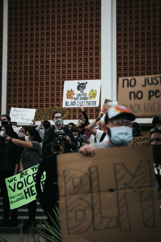 people hold signs as they protest in front of a building