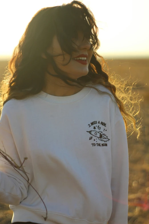 a woman standing in an empty field wearing a white shirt