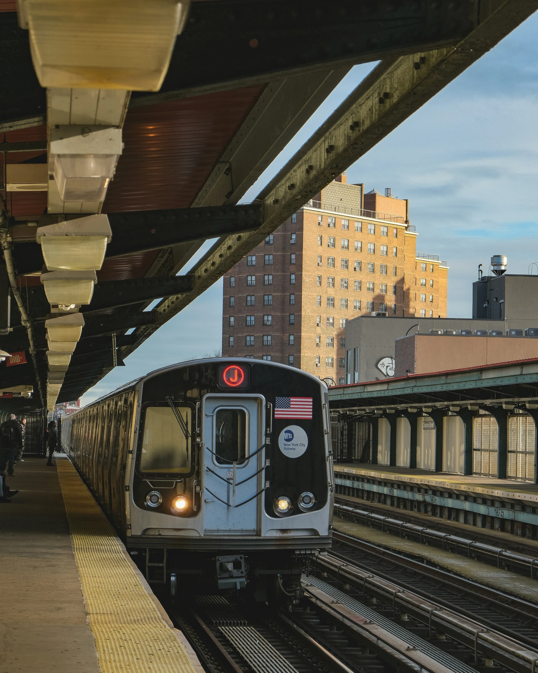 a subway train pulling into the station with buildings in the background