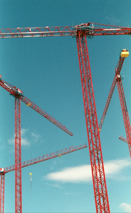 some cranes under a partly cloudy blue sky