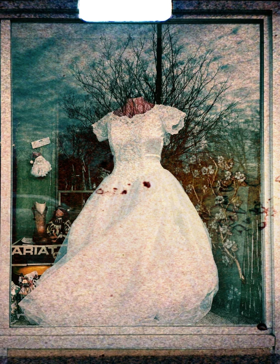 a white dress sits on display in an antique frame