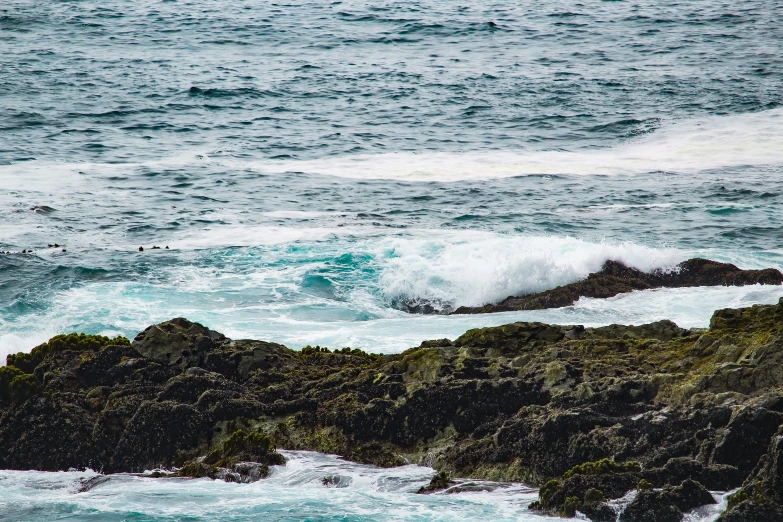 a surfer in white is riding his board on the rock