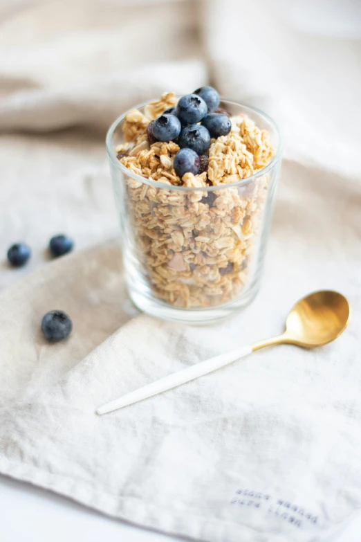 blueberries and granola in a glass on a cloth
