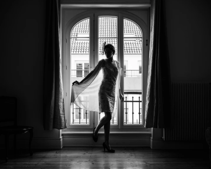 a woman in a dress is standing in front of a window