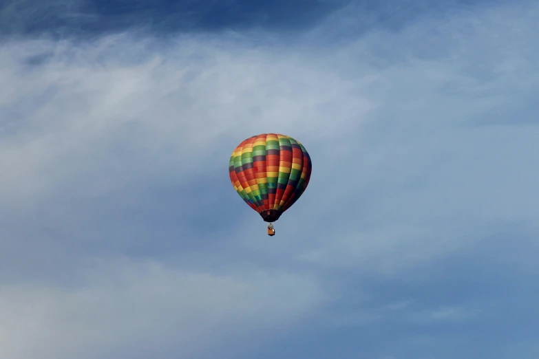 a colorful  air balloon flying through a cloudy sky